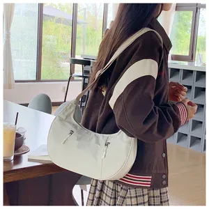 Close-up of off-white nylon crescent bag with adjustable strap and functional zippers