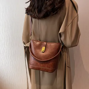Retro brown bucket bag with gold lock buckle and distressed leather texture for autumn