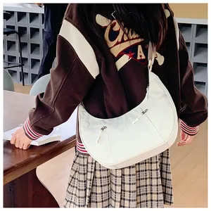 Detail view of off-white crescent crossbody bag with functional side zippers and nylon texture