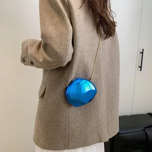Metallic blue mirror evening bag with gold chain strap shown on a cross-body model