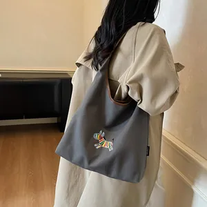 Large dark grey canvas tote bag with colorful zebra embroidery and brown leather straps