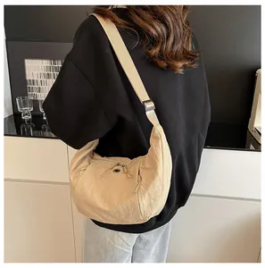 Close-up of beige nylon crescent bag featuring wide adjustable strap and dual zippers