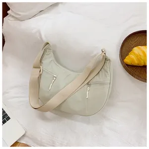 Detailed view of mint green nylon crescent bag with dual front zipper pockets and wide strap