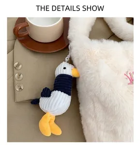 Detail of cute striped bird plush charm hanging on white faux fur shoulder bag