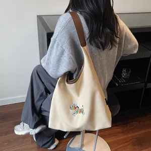 Canvas tote bag with animal embroidery and brown leather shoulder straps in a home setting
