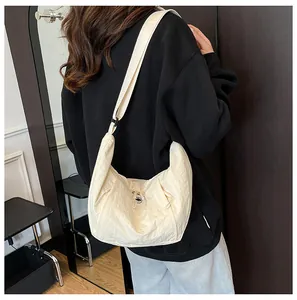 Detail of beige crescent shoulder bag showing pleated nylon fabric texture and metal buckle