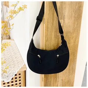 Detail of black nylon crescent bag with double zipper pockets and adjustable strap