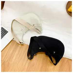 Detail of minimalist nylon crescent bags in beige and black with wide straps