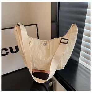 Detail of off-white crescent crossbody bag with textured fabric and adjustable strap