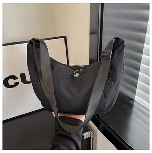 Close-up of black nylon crescent tote bag featuring adjustable strap and zipper detail
