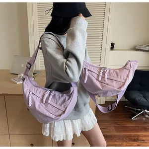 Close-up of light purple nylon dumpling bag with adjustable strap and woven zipper pull