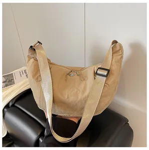 Detail of khaki crescent crossbody bag with nylon texture and adjustable strap