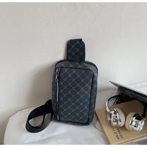 Detailansicht einer grauen Monogramm-Brusttasche mit Metallreißverschluss und Laptop-Zubehör