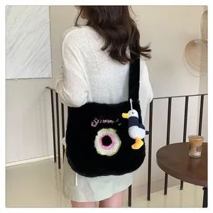Detail of black plush shoulder bag featuring donut embroidery and a cute duck pendant