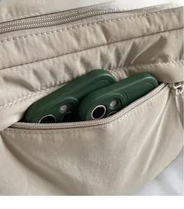 Close-up of functional side zipper pocket on beige nylon bag showing storage capacity