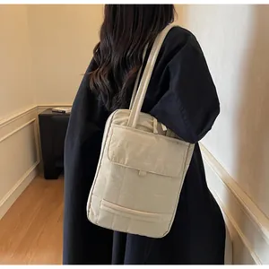 Detail view of the cream-colored textured tote bag showing side strap and multi-pocket design