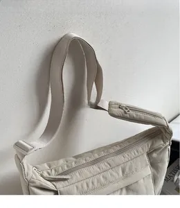 Detail of beige quilted nylon crossbody bag featuring an adjustable wide fabric strap