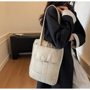 Detail of quilted beige laptop bag with front pocket showing fabric texture and design