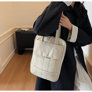 Detail of minimalist beige nylon tote bag with quilted lines and large front pocket