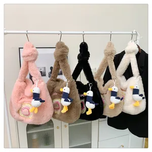 Plush lamb wool shoulder bags in five colors with cute duck pendants on a white rack