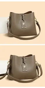 Détail du sac seau en cuir marron avec breloque rose dorée et bandoulière large