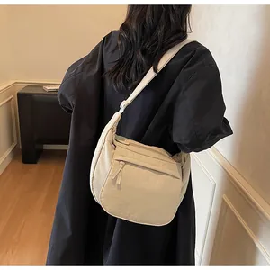 Close-up of beige moon bag texture and adjustable strap showing the practical side pocket