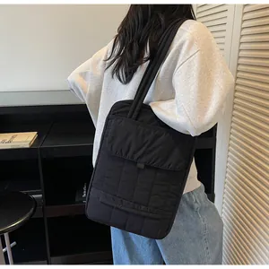 Vertical quilted black tote bag on shoulder showing large capacity and stylish commuting look
