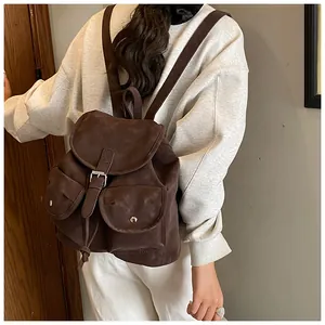 Vue détaillée du sac à dos en daim marron avec boucles métalliques et poches latérales