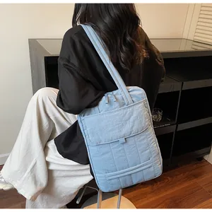 Detail of light blue quilted tote bag with front pocket showing texture and capacity