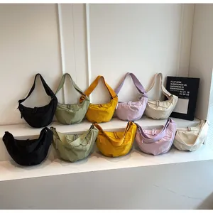 Detailed display of five color options for the nylon dumpling crossbody bag on a marble stand