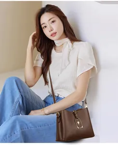 Détail du sac à main vintage en cuir marron avec breloque florale or rose et bandoulière
