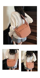 Detail of a pink large capacity nylon crossbody bag with zipper pocket and fabric strap