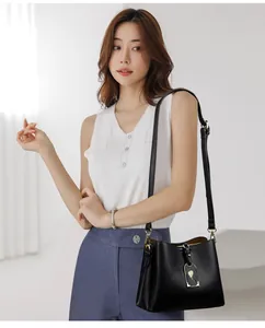 Détail du sac à main en cuir grainé noir avec pendentif floral doré et finitions en métal