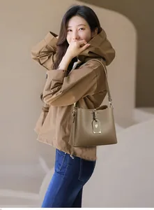 Gros plan sur la texture cuir litchi marron et détails métalliques du sac seau