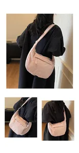 Detail of pink nylon crescent bag featuring a front zipper pocket and adjustable strap