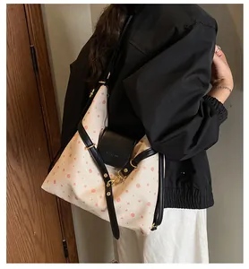 Detail view of canvas tote featuring pink polka dots and black leather shoulder strap