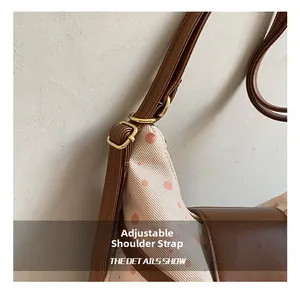Detail of adjustable leather shoulder strap with gold buckle on polka dot canvas tote bag