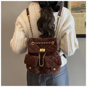 Detail of dark brown quilted corduroy backpack with gold chain straps and turn-lock closure