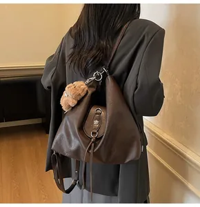 Detail view of a brown vintage tote bag featuring a cute plush bear charm and metal flower