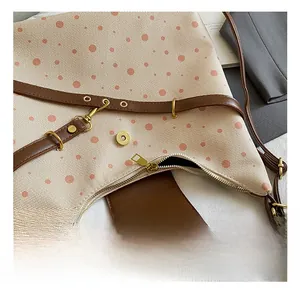 Close-up of beige canvas shoulder bag with pink dots and premium golden hardware details