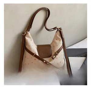 Detail of canvas bag with polka dots, leather trim, and golden metal buckle decoration