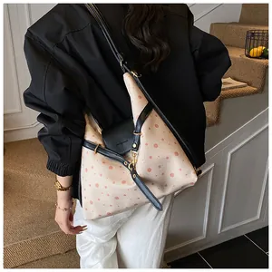 Detail of canvas shoulder bag with pink polka dots and black leather trim for women