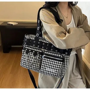 Detail of houndstooth tote bag featuring front zipper pockets and metallic rivet accents