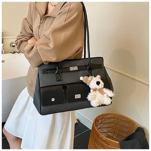 Detail of a grey tote bag with metal buckle closure and cute white bear charm accessory