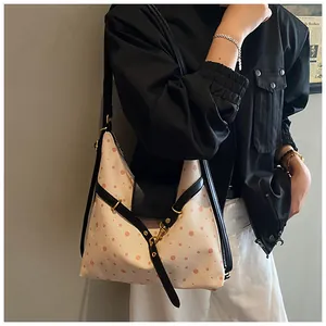 Polka dot canvas shoulder bag with leather straps shown worn by a side-view model