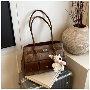 Detail of vintage brown tote bag with metal twist locks and a plush bear pendant accessory