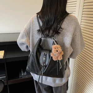 Minimalist black faux leather tote bag with floral buckle and plush bear charm