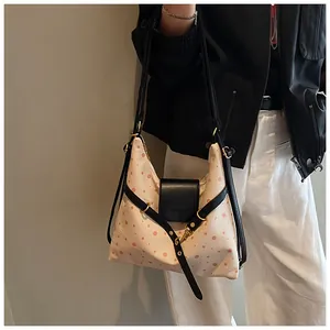 Detailed side view of canvas polka dot crescent bag with leather strap and metal buckle