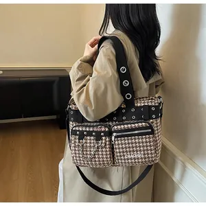 Detail of punk style houndstooth tote bag with silver rivets and metal chain decor