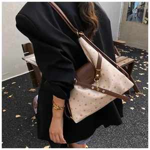Detail of canvas tote bag with pink polka dots and brown leather strap on model